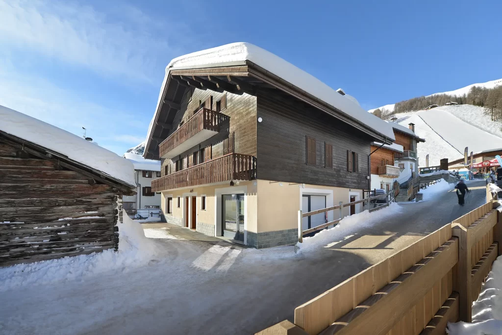 Chalet di montagna innevato con cielo sereno.