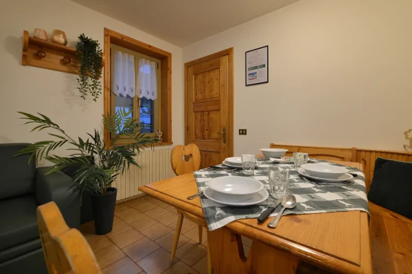Sala da pranzo accogliente con tavolo apparecchiato, sedie in legno e decorazioni in stile rustico.
