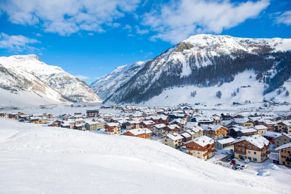 Vista panoramica di un villaggio alpino innevato circondato da montagne.